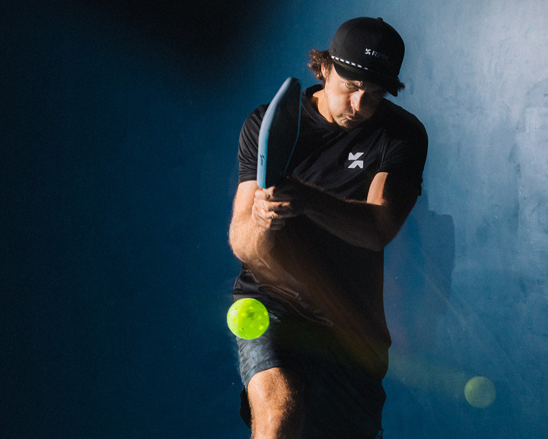 A male pickleball player in action, mid-swing.