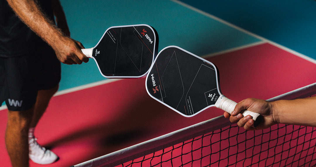 Two pickleball paddles held by players on a pickleball court