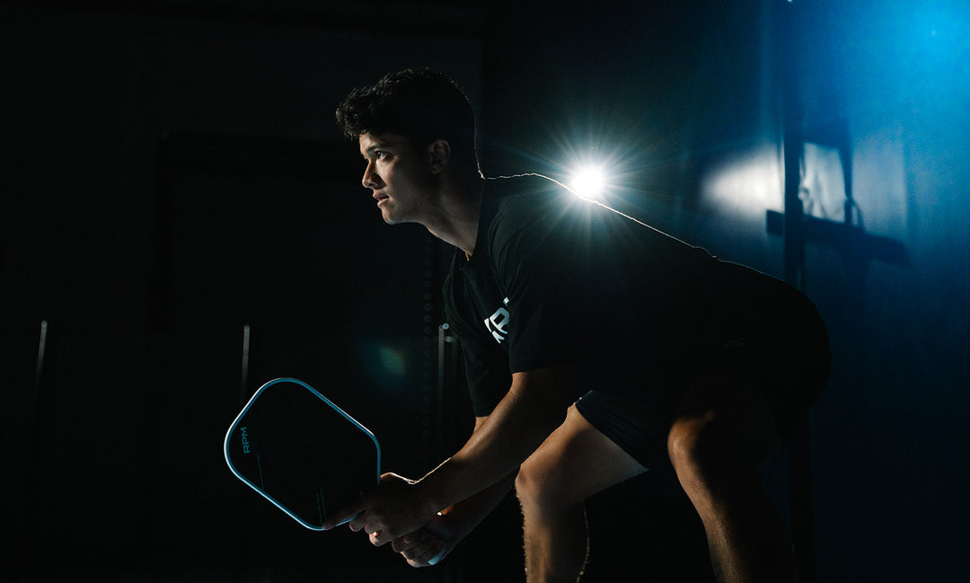 Ryan Fu preparing for a return in a dark room with a light behind him