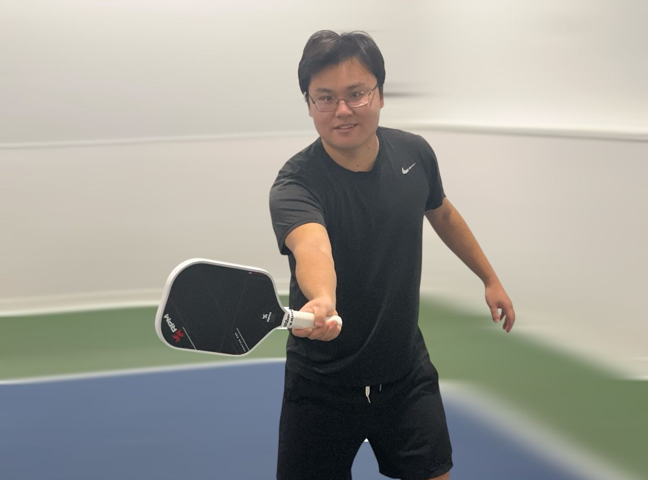 A male pickleball player in action, mid-swing.